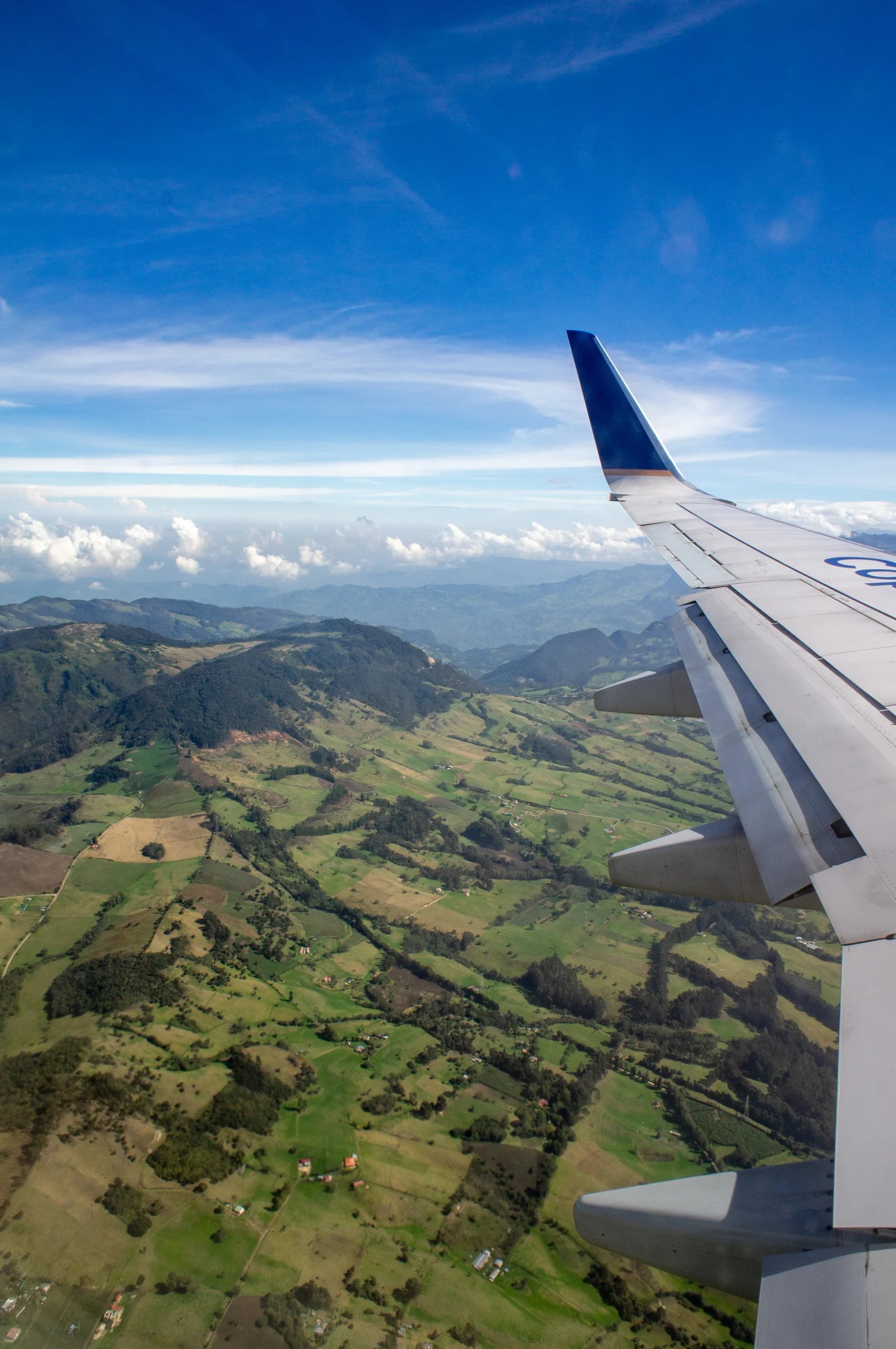 The green folds of the Andes seen past an aircraft wing, cloud banked along the horizon