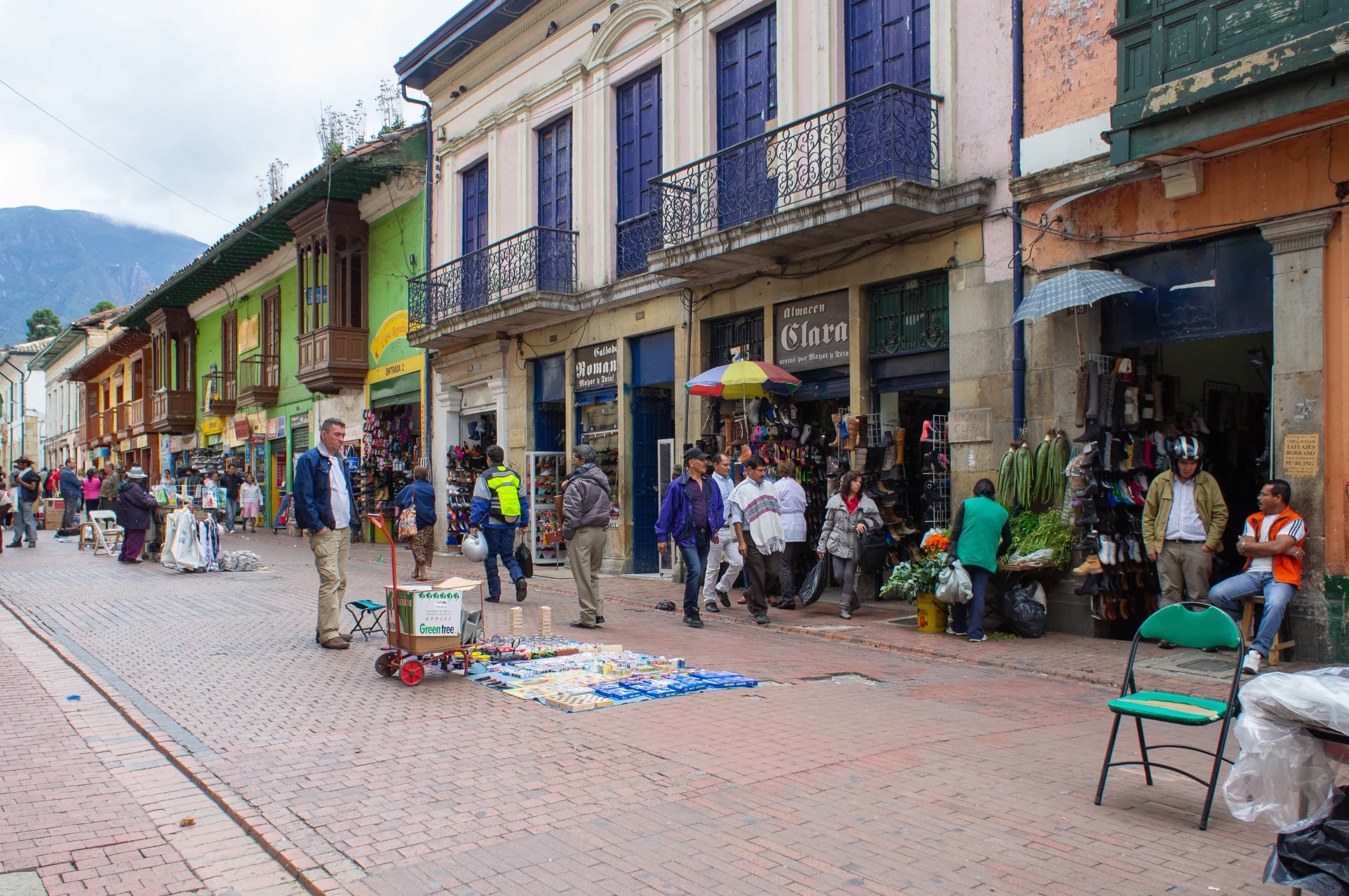 Shoppers and street vendors along a colonial arcade in central Bogota, awnings and iron balconies above the shopfronts