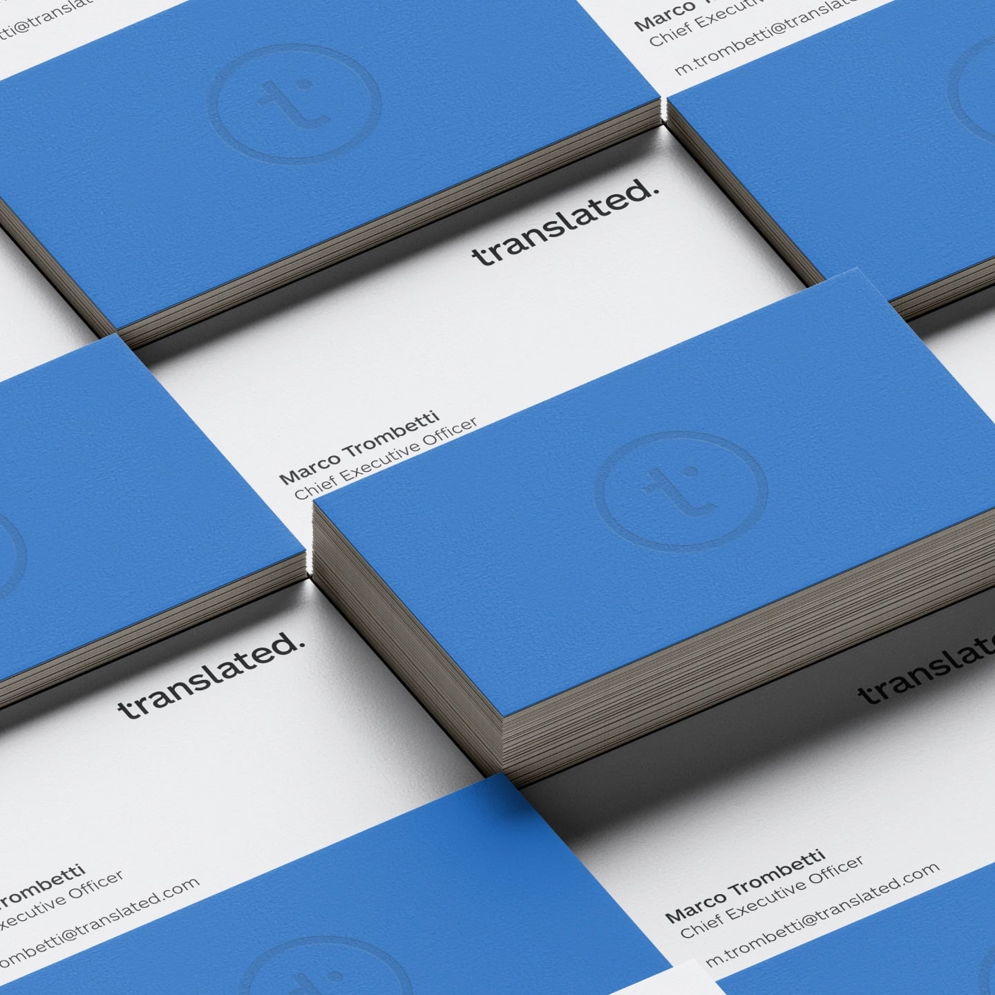 Business cards in a tiled grid, blue backs with a blind-embossed t mark facing white fronts with the wordmark and contact details